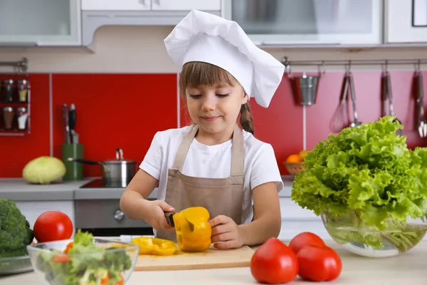 Маленькая девочка режет овощи — стоковое фото