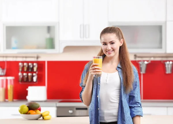 年轻美丽的女人在厨房喝果汁 — 图库照片