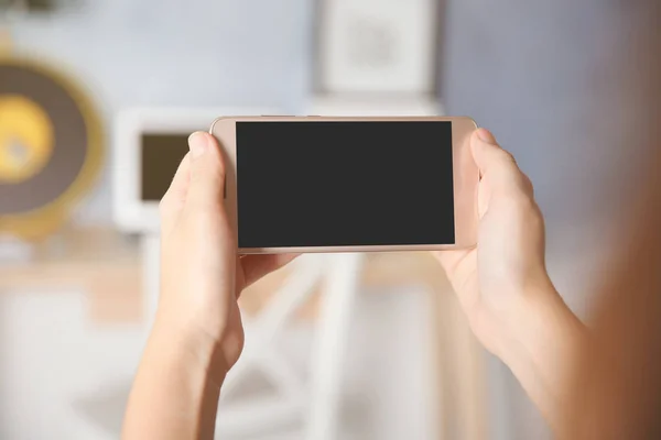 Mujer sosteniendo el teléfono celular moderno en casa —  Fotos de Stock