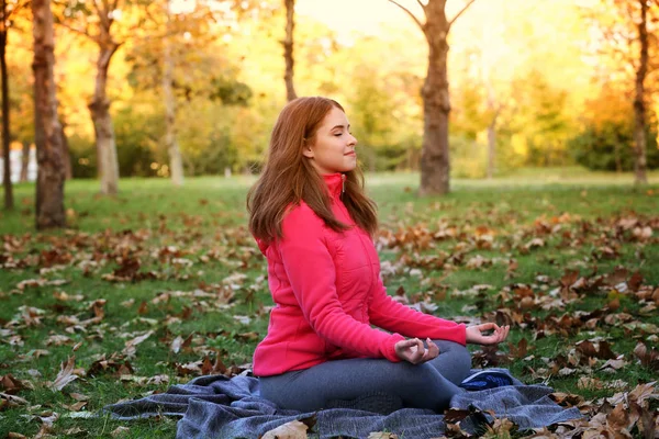Young beautiful woman doing yoga in autumn park