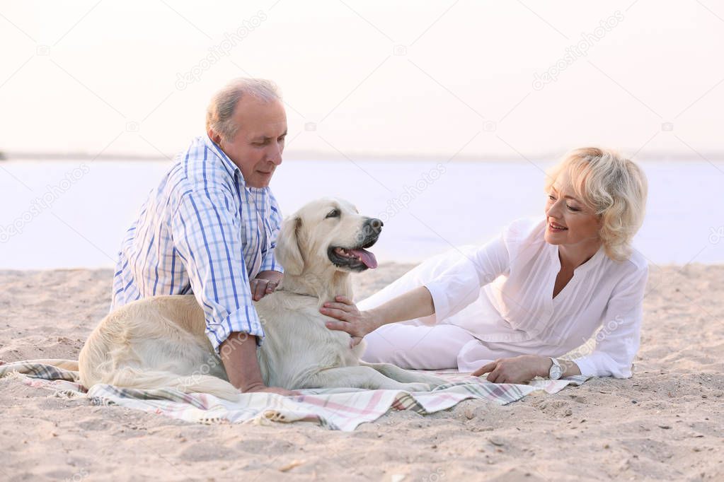 Senior couple and dog sitting on plaid 