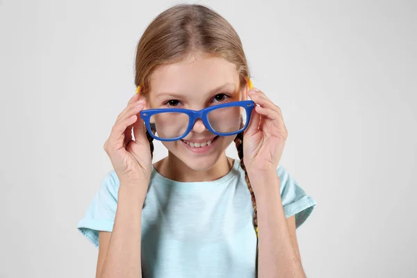 Маленькая девочка в очках на светлом фоне — стоковое фото