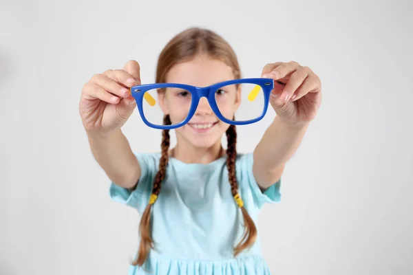 Kleines Mädchen mit Brille auf hellem Hintergrund — Stockfoto
