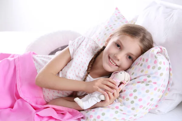 Little girl with bunny toy in bed at home