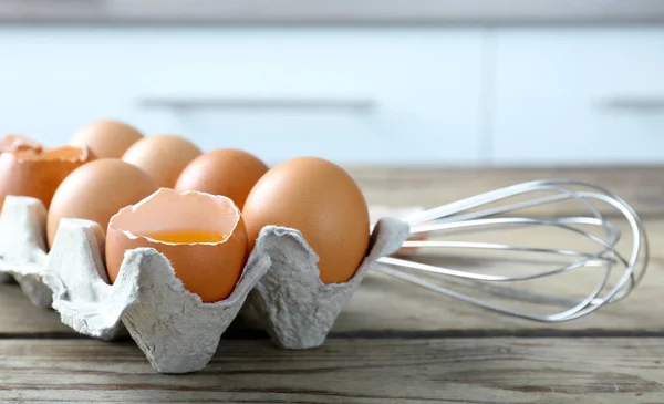 Surowe jaja w pakiecie z trzepaczką — Zdjęcie stockowe