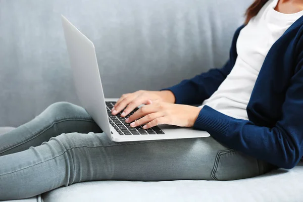 Милая девушка сидит на диване с ноутбуком — стоковое фото