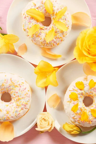 Тарелки с вкусными пончиками и цветами — стоковое фото