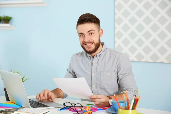 Unga manliga dekoratör sitter vid skrivbord i office — Stockfoto