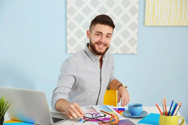 Junger männlicher Dekorateur sitzt am Schreibtisch im Büro — Stockfoto
