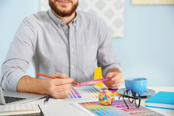 Unga manliga dekoratör sitter vid skrivbord i office — Stockfoto