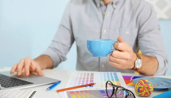 Unga manliga dekoratör sitter vid skrivbord i office — Stockfoto