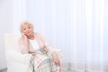 Yaşlı kadın yüz koltuk ışık odasında otururken yaslanır