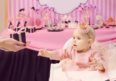 Parti için dekore edilmiş oda yüksek sandalyede oturan sevimli küçük doğum günü kızı için mevcut veren anne