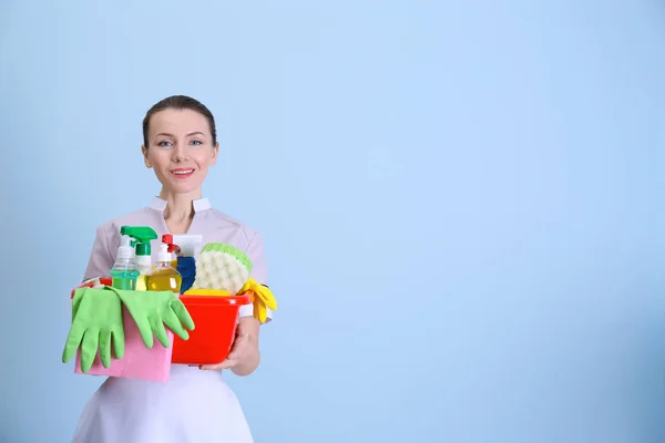 Beautiful chambermaid with cleaning equipment on color background — Stock Photo, Image