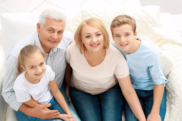 Cute children with grandparents sitting on sofa in living room