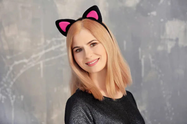 Bella giovane donna con orecchie di gatto su sfondo grunge — Foto Stock