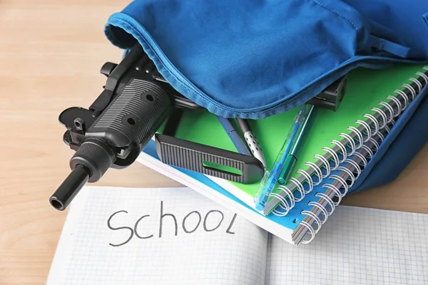 Skolan ryggsäck med böcker, pappersvaror och gun på skrivbord — Stockfoto