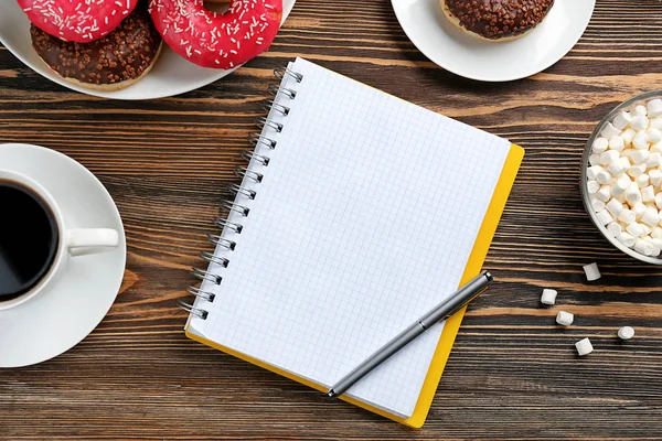 Velsmagende donuts med kop kaffe og notesbog - Stock-foto