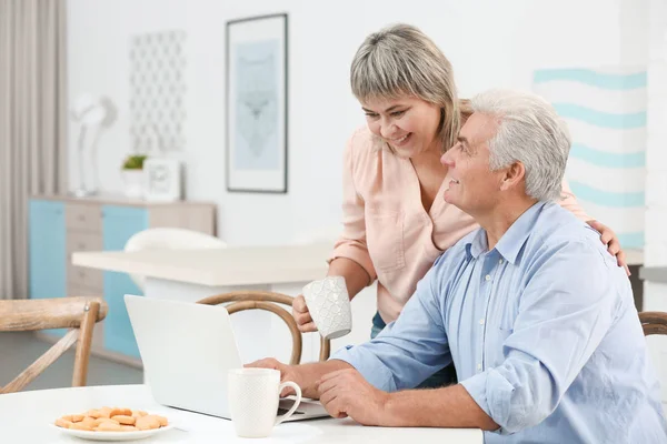 Casal de meia idade com laptop na cozinha — Fotografia de Stock