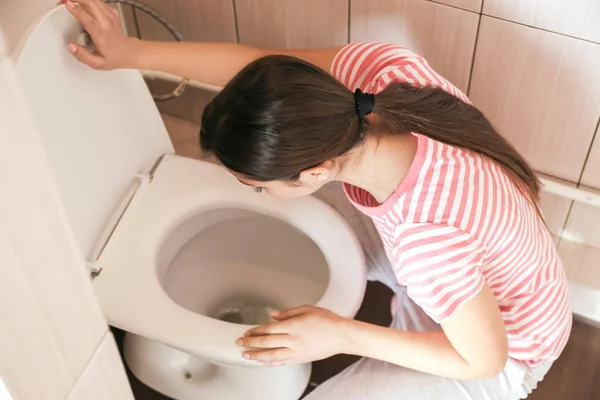 Mujer joven vomitando cerca del inodoro en casa — Foto de Stock