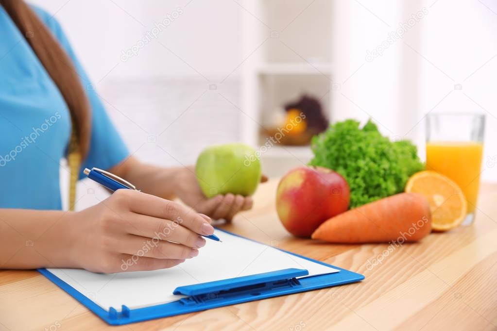 Female nutritionist counting calories in hospital, closeup