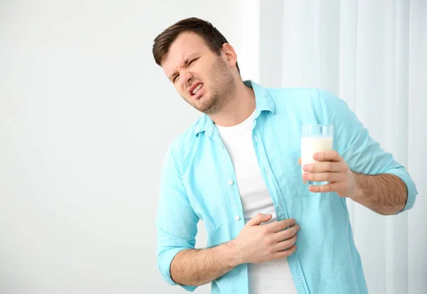 Молодой человек с аллергией на молоко держит стекло в руке — стоковое фото