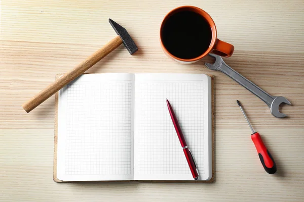 Notebook and repairing tools with cup of coffee