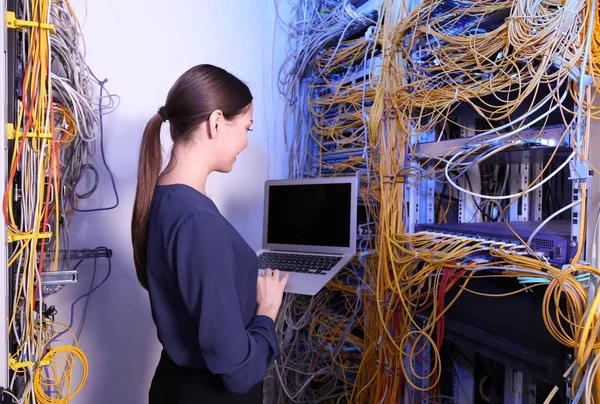 Beautiful young engineer with laptop in server room — Stock Photo, Image