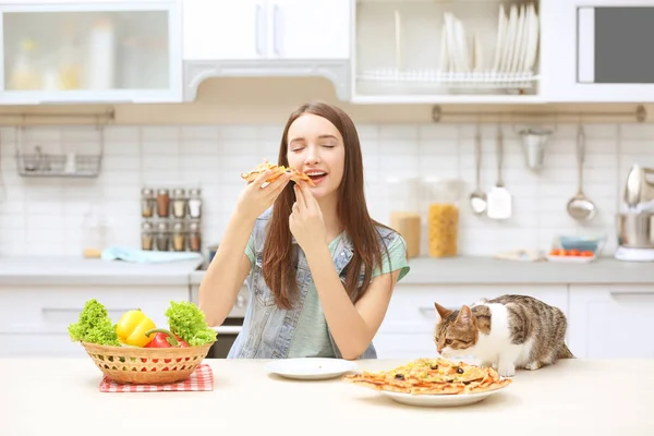 Genç kadın ve lezzetli pizza mutfakta yemek şirin kedi — Stok fotoğraf