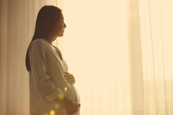 Έγκυος γυναίκα της Ασίας που στέκεται κοντά στο παράθυρο στο σπίτι — Φωτογραφία Αρχείου