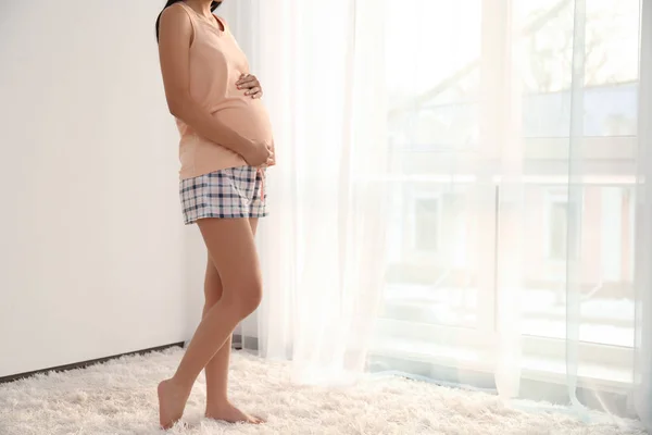 Hermosa mujer embarazada cerca de la ventana en casa — Foto de Stock