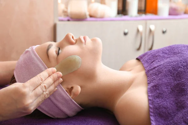 Face massage with jade stones in spa center