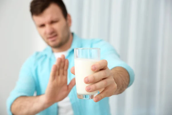 Jonge man met melk allergie glas in de hand houden — Stockfoto