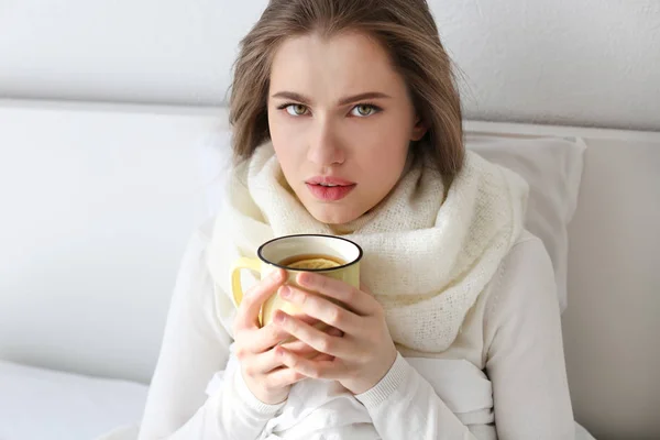 Mujer joven enferma con taza de té caliente en la cama en casa — Foto de Stock