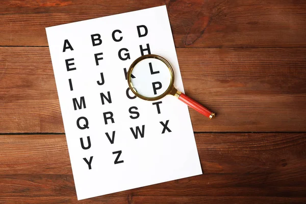 Paper with alphabet and magnifier — Stock Photo, Image