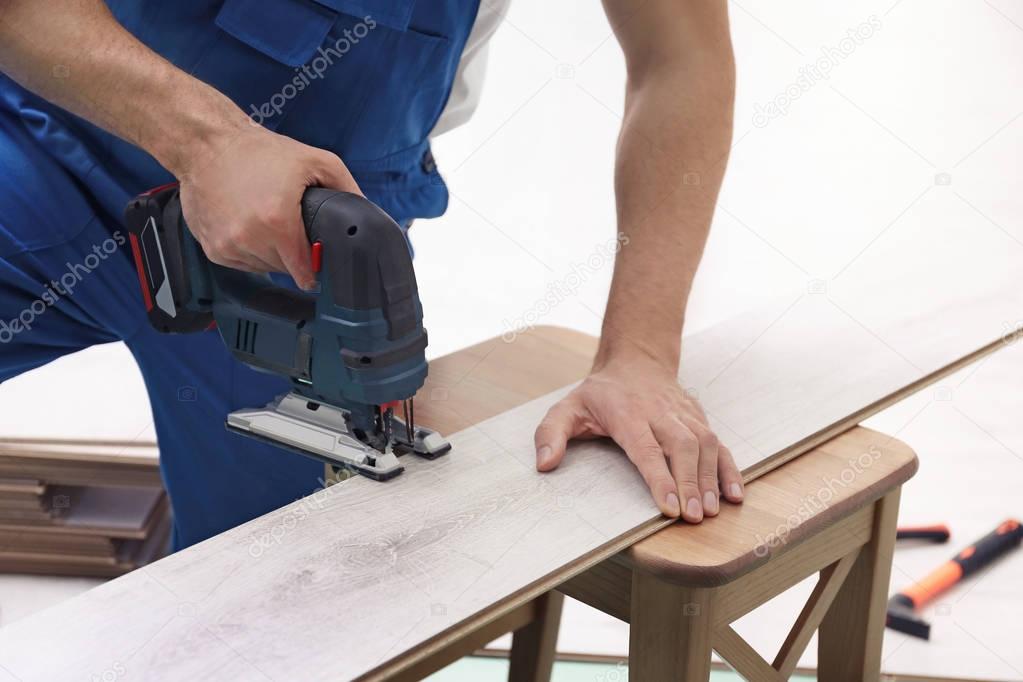 Man cutting laminate board with jigsaw