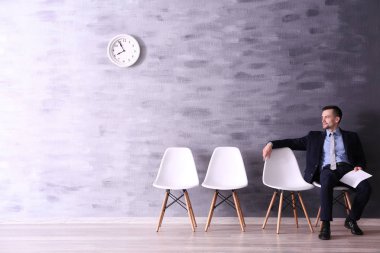Resepsiyon salonunda iş görüşmesi için bekleyen genç adam