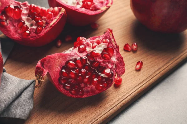 Wooden board with ripe pomegranates — Stock Photo, Image