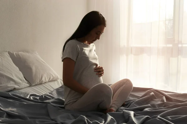 Terhes ázsiai nő ül ágyas otthon — Stock Fotó