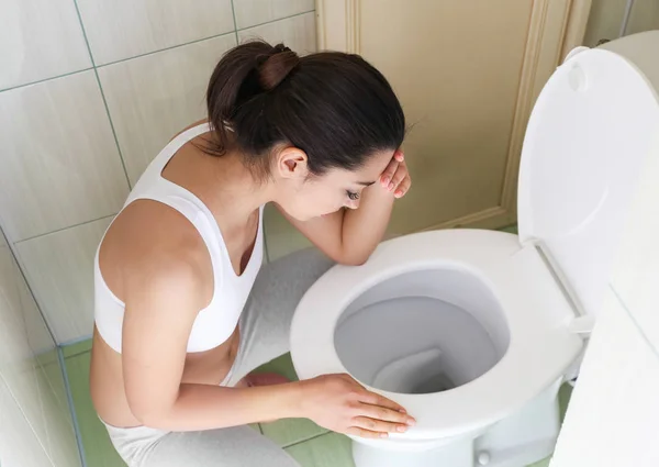 Jeune femme vomissant près du bol de toilette à la maison — Photo
