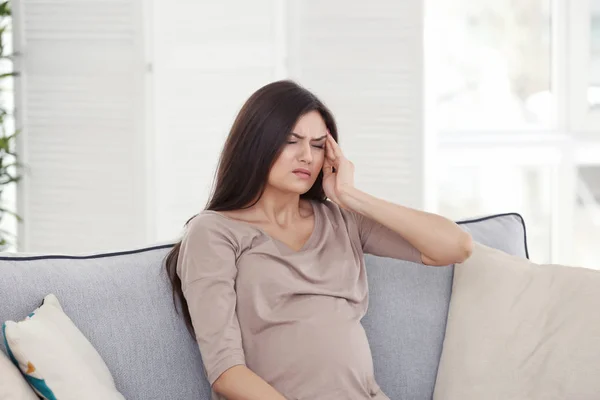 Mujer embarazada joven que sufre de dolor de cabeza en casa —  Fotos de Stock