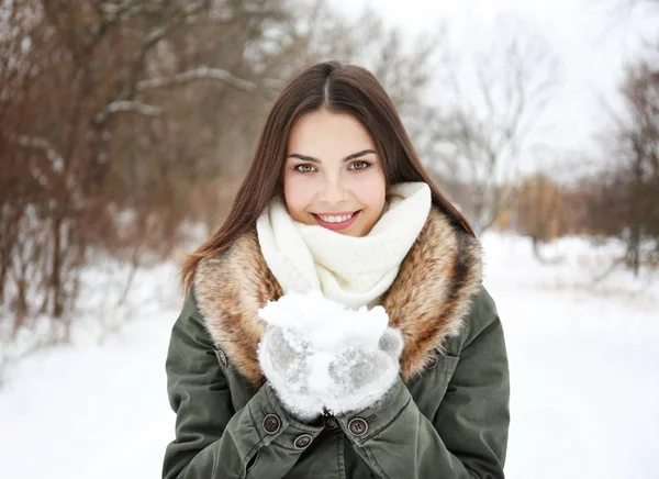 Retrato de jovem mulher bonita brincando com neve no parque de inverno — Fotografia de Stock