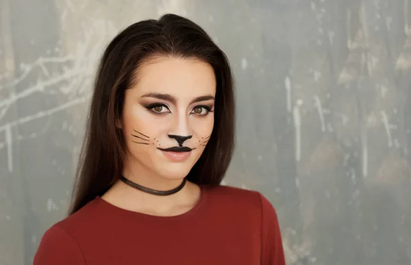 Vacker ung kvinna med katt makeup på grunge bakgrund — Stockfoto