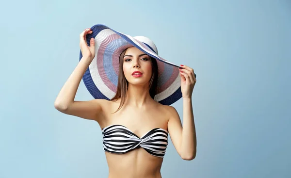 Junge schöne Frau mit Hut auf hellem Hintergrund — Stockfoto