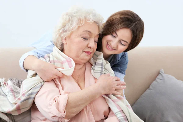 Mooi meisje bedekking grootmoeder met deken op de Bank thuis — Stockfoto