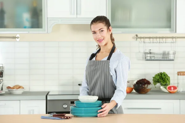 Vrouw Schort Holding Gerechten Keukentafel — Stockfoto
