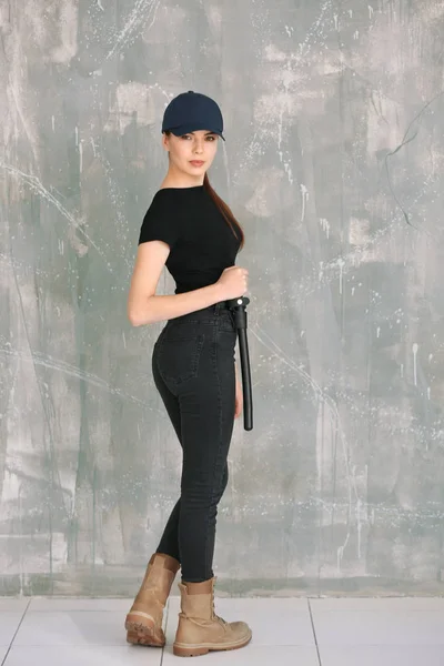 Vacker ung kvinna i säkerhet uniform stående nära grunge wall — Stockfoto