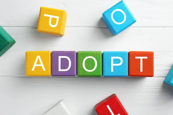 Cubos de colores con palabra ADOPT —  Fotos de Stock