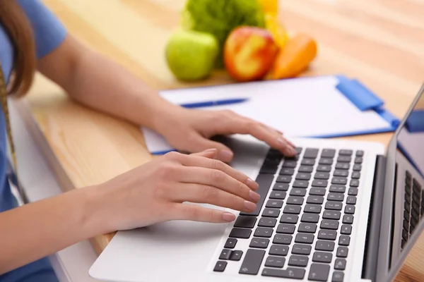 Unga kvinnliga dietist arbetar med laptop i office, närbild — Stockfoto
