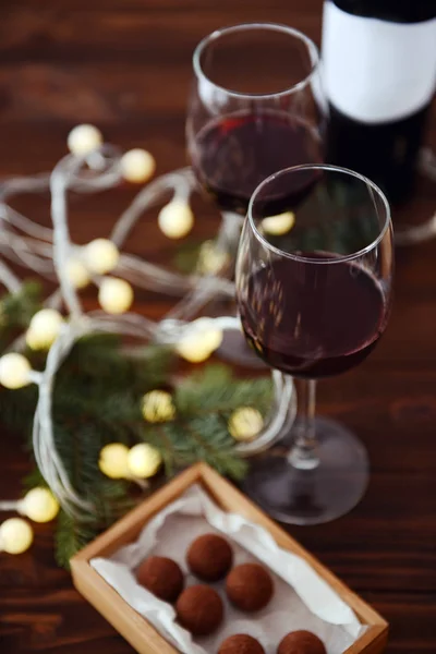 Glasses of wine and chocolates with garland — Stock Photo, Image